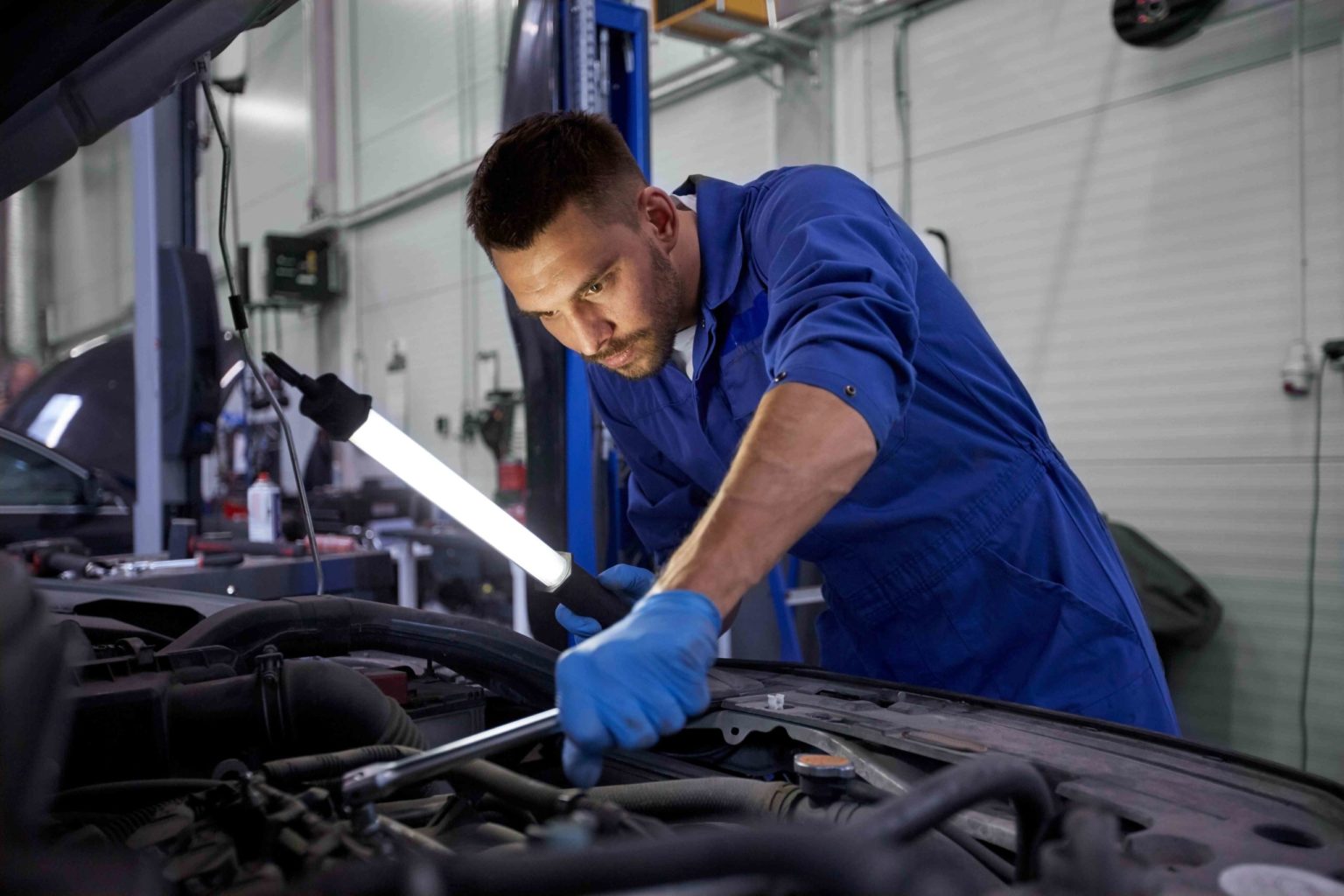 auto repair technician using light to see engine